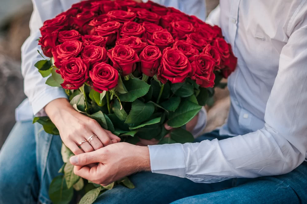 Couple holding a large bouquet of roses