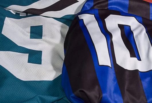 Close-up of a green jersey with the number "9" and blue/black striped jersey with the number "10"