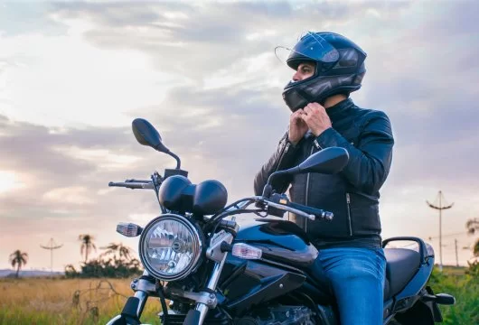 Man sitting on his motorcycle adjusting his helmet