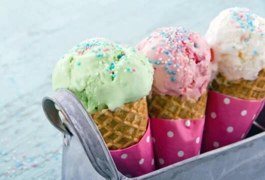 Three ice cream cones with sprinkles in a carrier