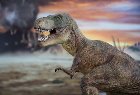 Model of a T. Rex dinosaur in front of a volcano