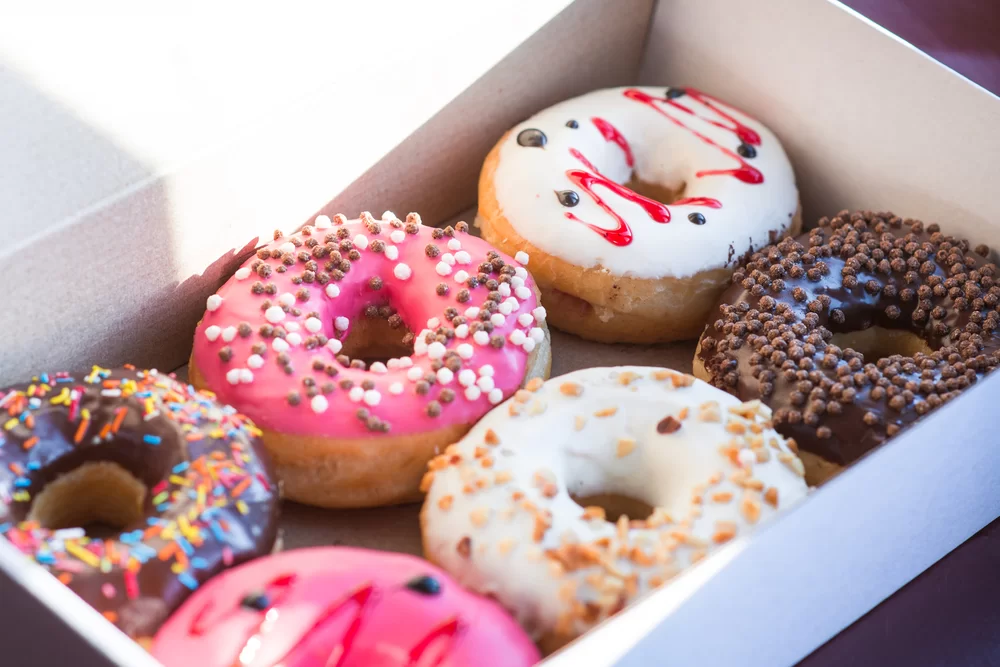 Box of doughnuts with colorful icing and toppings