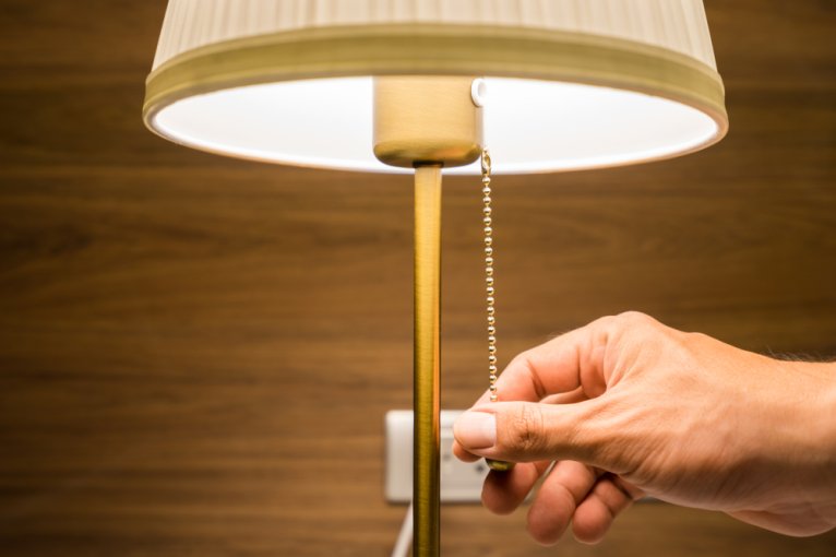 Close-up of a person's hand turning off a lamp, which starts with "l"
