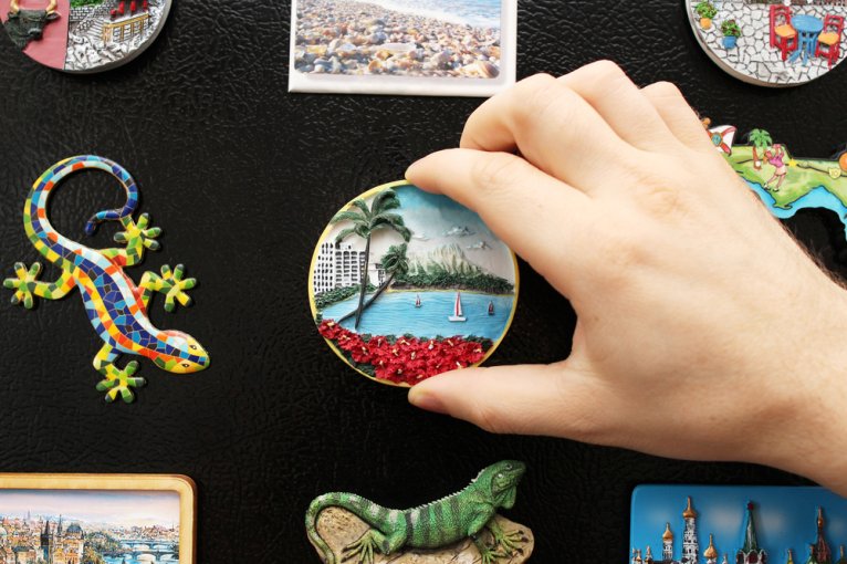 Close-up of person's hand placing a magnet on the refrigerator