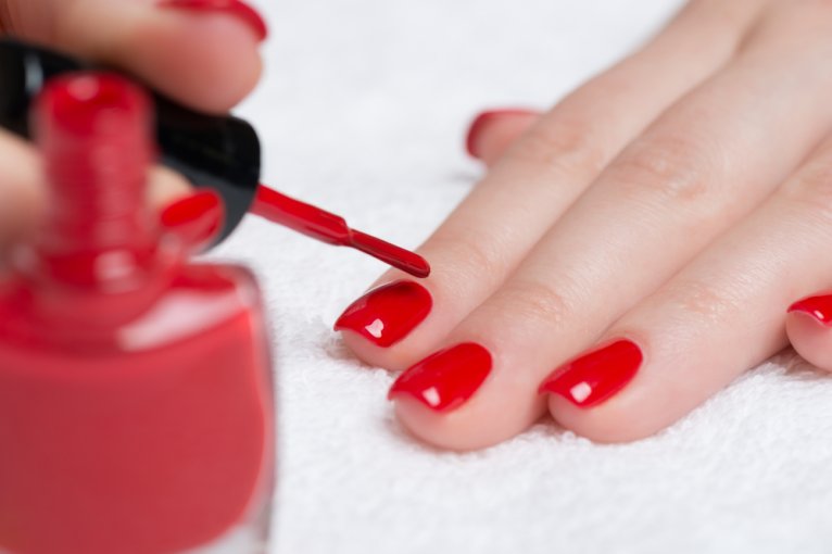 Woman using red nail polish to paint her nails