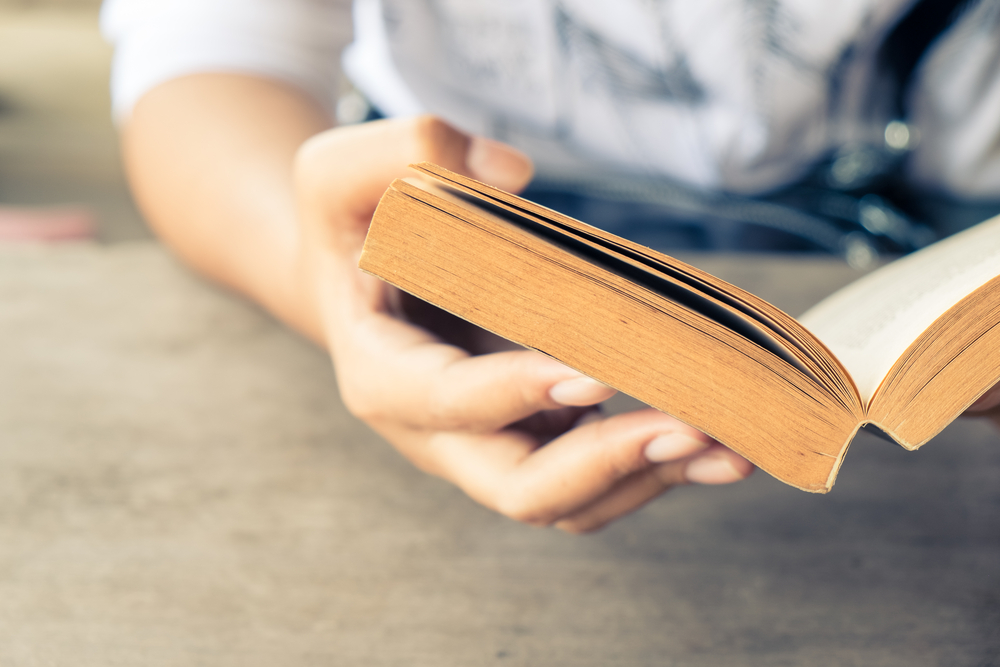 Close-up of person's hand holding a paperback book