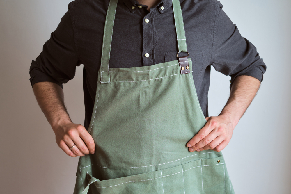 Close-up of man tying on a green apron
