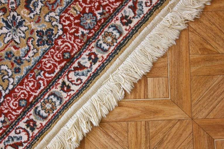 Close-up of a red patterned rug with white fringe