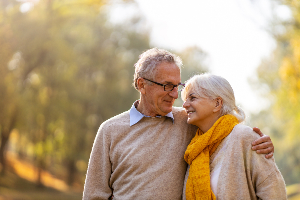 Older couple walking closely outdoors in the fall