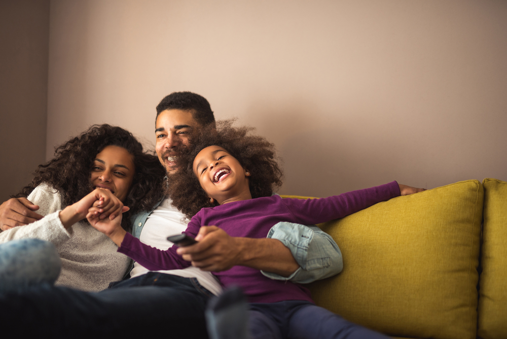 Young, loving family smiling and hugging on a couch