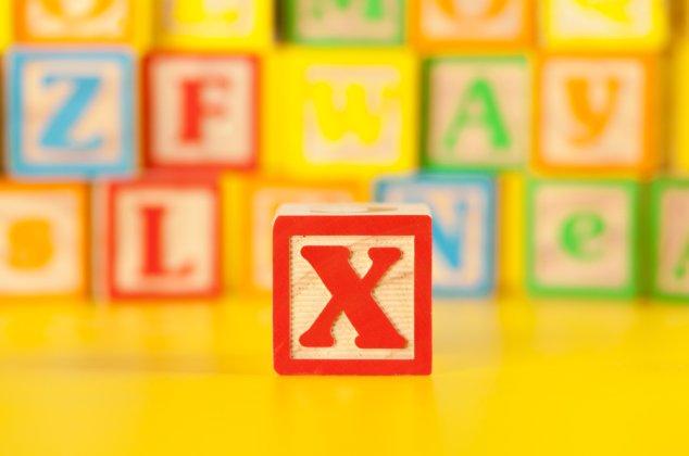 Letter "X" block in focus in front of a stack of other letter blocks