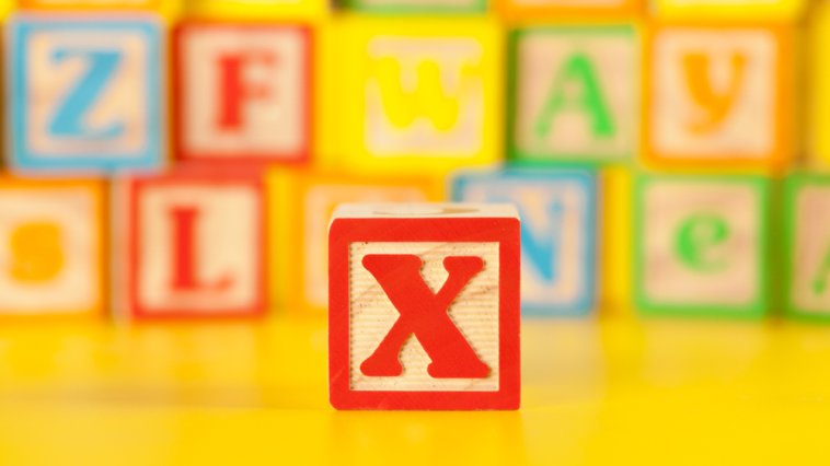 Letter "X" block in focus in front of a stack of other letter blocks