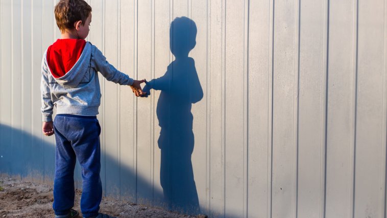 Young boy pointing at his "imaginary friend" shadow