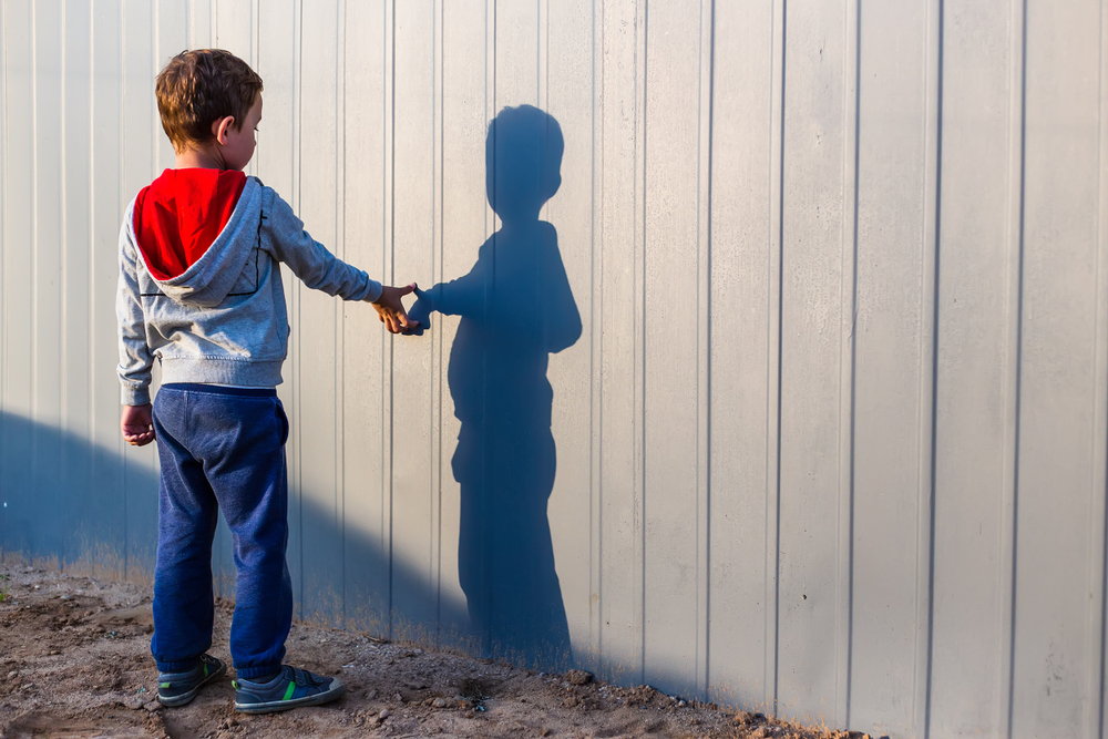 Young boy pointing at his "imaginary friend" shadow
