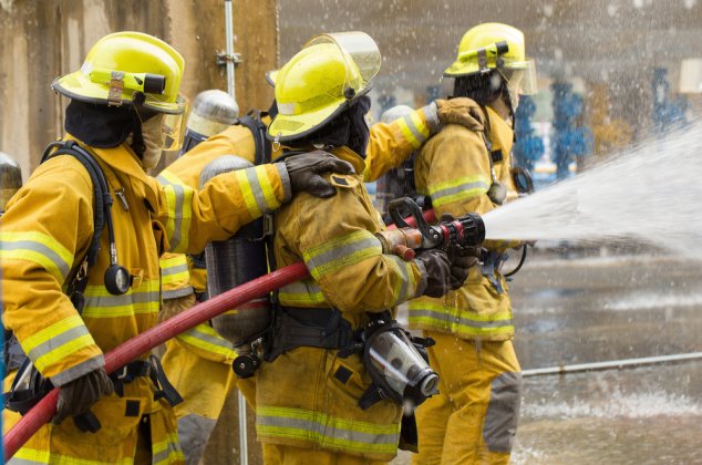 Firefighters spraying water at the site of a fire