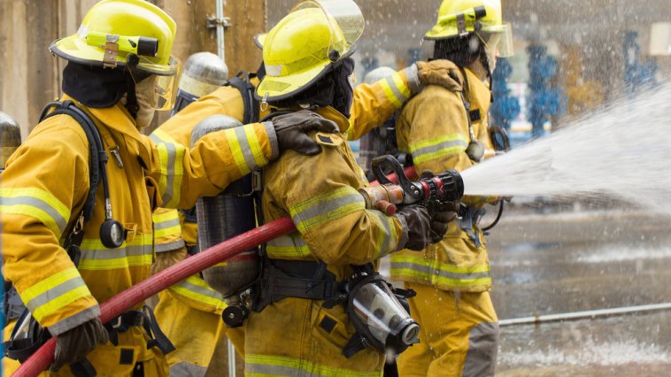 Firefighters spraying water at the site of a fire