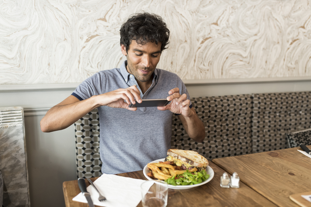 Foodie taking a picture of his plate at a restaurant