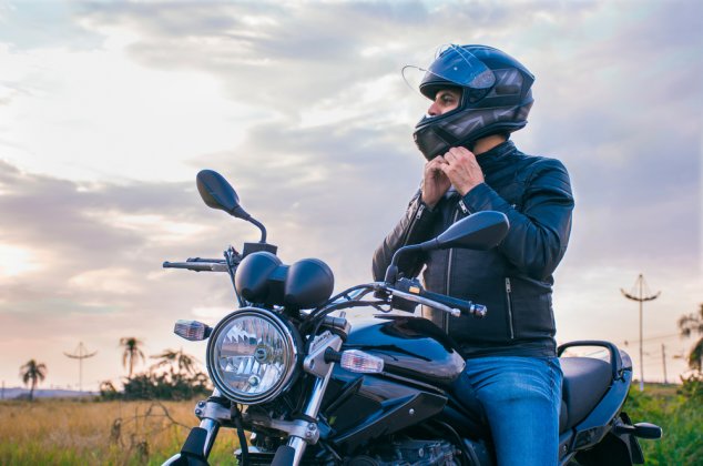 Man sitting on his motorcycle adjusting his helmet