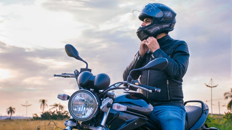 Man sitting on his motorcycle adjusting his helmet