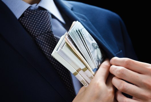 Corrupt man stuffing money into his suit jacket