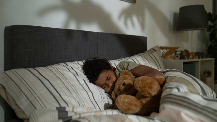 Child hugging a teddy bear during a nightmare