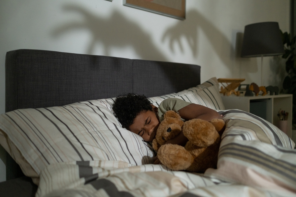 Child hugging a teddy bear during a nightmare