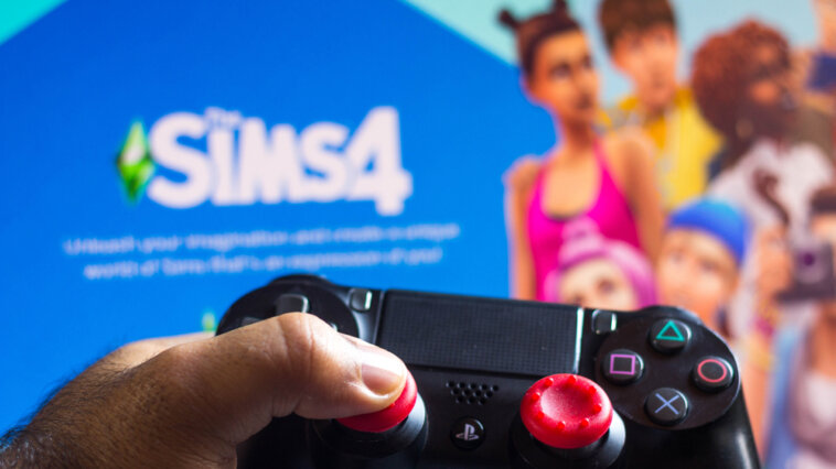 Game controller shown in front of a screen loading The Sims 4
