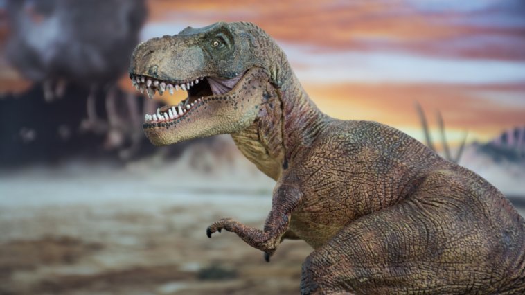 Model of a T. Rex dinosaur in front of a volcano