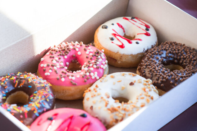 Box of doughnuts with colorful icing and toppings