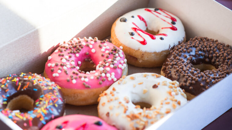 Box of doughnuts with colorful icing and toppings