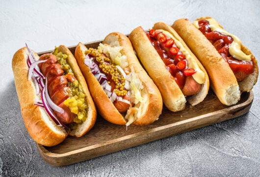 Four hot dogs with different toppings on a platter